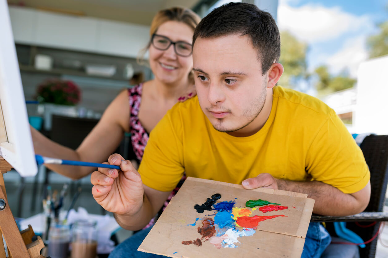 disabled boy painting with blonde woman