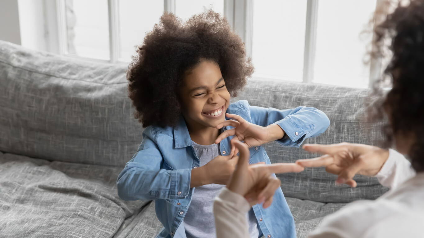 little girl with a big smile signing to an adult