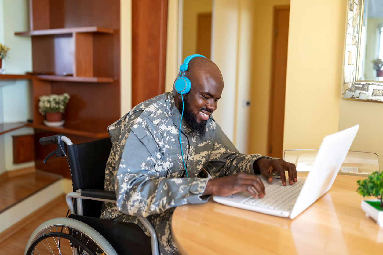 man in military uniform in wheelchair on laptop with head phones ss disability access