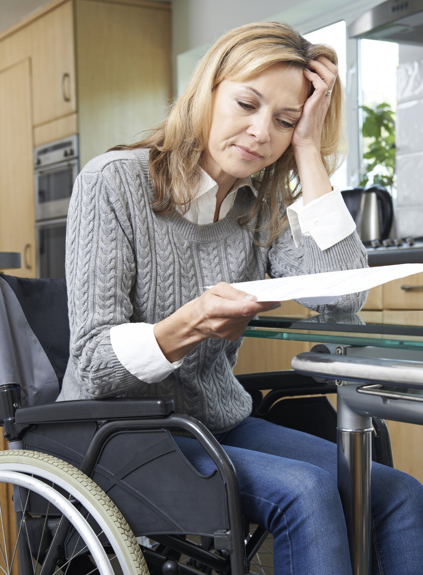 frustrated woman in wheelchair reading official document