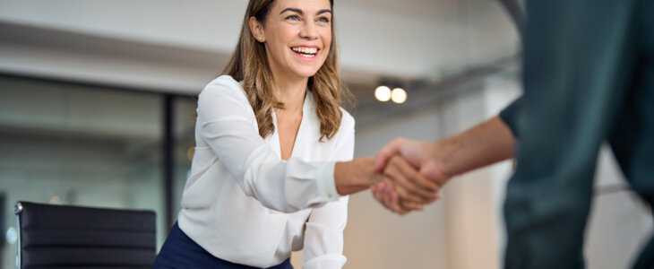 Happy mid aged lawyer woman handshaking greeting client in office.