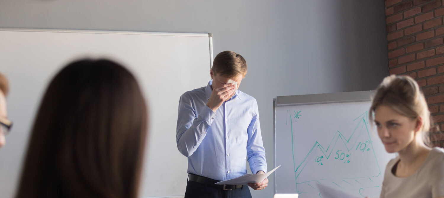 Stressed male speaker or presenter worried before making presentation for colleagues in meeting room, nervous employee wipe face scared to speak in public, afraid to present business report in office.
