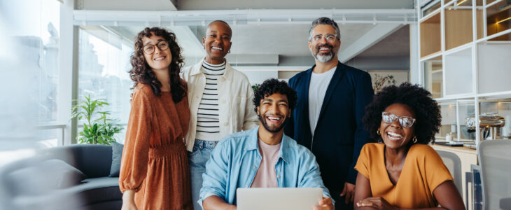 Successful business team working together in an office. They are happy, smiling and looking at the camera, representing their thriving startup company.