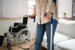Hurt Leg Using Crutches Near Wheelchair At Home
